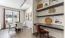 a room with a table chairs and a shelf with art on it