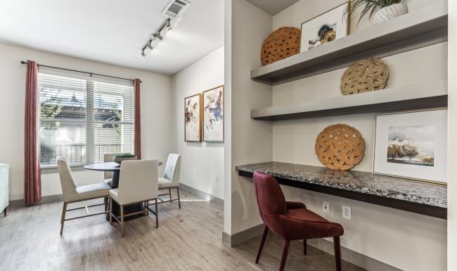 a room with a table chairs and a shelf with art on it